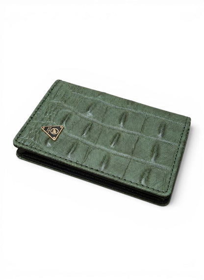 Green crocodile-patterned wallet with a gold emblem on a white background by Mint Worldwide.