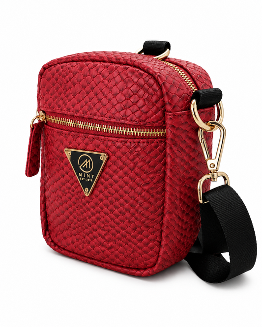 Red quilted crossbody bag with gold accents on a white background