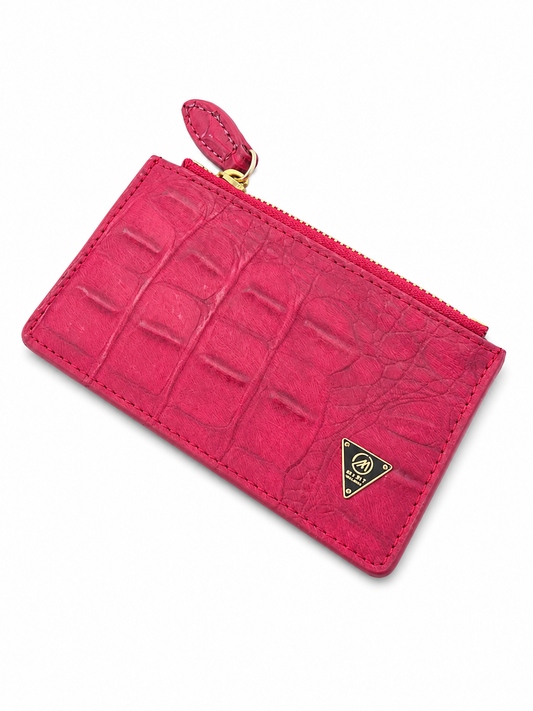 Pink crocodile-patterned wallet with a gold zipper on a white background